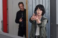 Kommissar van der Valk – Inspector Lucienne (Maimie McCoy) eilt van der Valk zu Hilfe und bemerkt dabei nicht, wie sich einer von Vissers Handlangern (Christian Petersson) an sie ran schleicht.