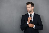 111 – Perfect to the last detail. Handsome young businessman adjusting his sleeves while standing against grey background