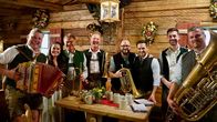 Servus Musikantenstammtisch – Moderator Richard Deutinger (3.v.r.) posieren für ein Foto mit der Schönleitn Musi.
