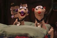 Unser Sandmännchen – Die Erdmännchen Jan und Henry sitzen mit Glocken um den Hals in ihrem Bett.