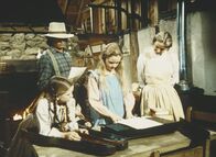 Unsere kleine Farm – Laura (Melissa Gilbert, l.), Charles (Michael Landon, 2.v.l.), Mary (Melissa Sue Anderson, M.) und Caroline (Karen Grassle) bestaunen ein Musikinstrument.
