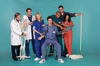 Scrubs - Die Anfänger – (2. Staffel) - Die Truppe vom Sacred Heart Hospital: J.D. (Zach Braff, M.), Turk (Donald Faison, 3.v.r.), Dr. Phil Cox (John C. McGingley, 2.v.l.), Hausmeister (Neil Flynn, 2.v.r.), Dr. Bob Kelso (Ken Jenkins, l.), Elliot (Sarah Chalke, 3.v.l.), und Carla (Judy Reyes, r.) ...