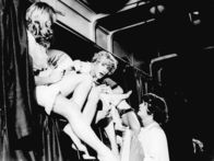 Manche mögen's heiß – Als (unbekannter) Hahn im Korb feiert Jerry (Jack Lemmon, 2. von links) alias "Daphne" im Schlafwagen nach Miami eine kleine Party mit seinen neuen Kolleginnen aus einer Damenkapelle. Joe (Tony Curtis, rechts), der sich in eine "Josephine" verwandelt hat, fragt sich, ob das wohl gutgehen wird.