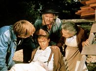 Die Waltons – Auf der Jagd nach einem Truthahn hat sich John-Boy (Richard Thomas, vorne M.) verletzt. Großvater Sam (Will Geer, hinten M.) und Großmutter Ester (Ellen Corby, r.) kümmern sich sofort um ihn ...