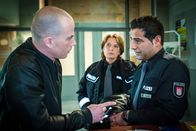 Notruf Hafenkante – Beim Verlassen des PK trifft Maslowski (Thomas Schumacher, l.) auf Tarik (Serhat Cokgezen, r.) und beleidigt ihn mit rassistischen Sprüchen. Claudia (Janette Rauch, M.) beobachtet die beiden.