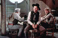 Mein großer Freund Shane – Ryker hat den Revolvermann Jack Wilson (Jack Palance - rechts) in die Stadt kommen lassen. Im Saloon gibt er sich selbstsicher und schüchtert andere ein.