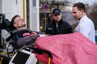 In aller Freundschaft – Der wegen Totschlag verurteilte Dennis Karow (Ilja Roßbander, li.) hat sich bei einem Fluchtversuch aus der JVA schwer verletzt. In Begleitung eines Polizisten (Komparse, mi.) wird er in der Sachsenklinik an Dr. Kai Hoffmann (Julian Weigend, re.) übergeben.