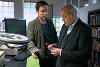 Wilsberg – Bruno Korati (Arnd Klawitter, l.) zeigt Georg Wilsberg (Leonard Lansink, r.) eine seiner Erfindungen: Eine Ansteck-Blume, mit der man jemanden überwachen kann. „