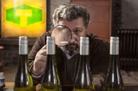Huck – Weinskandal: Cem (Aykut Kayacik) studiert mit einer Lupe die Riesling-Flaschen vom Weingut Ottinger.