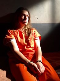 Married with Secrets – Shawna Nelson (Pamela Portnoy) sitzt mit Handschellen in einer Gefängniszelle.