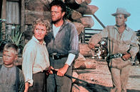 Mein großer Freund Shane – Die Familie Starrett (Brandon De Wilde, links; Jean Arthur, 2. von links; Van Heflin, 3. von links) ist besorgt wegen Rykers Bande, die sie bedroht. Shane (Alan Ladd, rechts) beobachtet ruhig und selbstsicher das Geschehen.