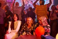 Hullraisers – Die Party ist ein voller Erfolg. Während die anderen auf der Tanzfläche feiern, sitzen Rana (Taj Atwal, l.), Toni (Leah Brotherhead, M.) und Paula (Sinead Matthews, r.) zusammen und genießen die ausgelassene Stimmung.