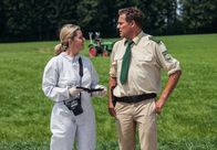 Hubert und Staller – ARD HEITER BIS TÖDLICH - HUBERT UND STALLER FOLGE 34, "Viel Wind um nichts" Uhr im ERSTEN. Dr. Anja Licht (Karin Thaler, l.) zeigt Hubert (Christian Tramitz, l.) das Foto einer Frau aus der Geldbörse des Toten.
